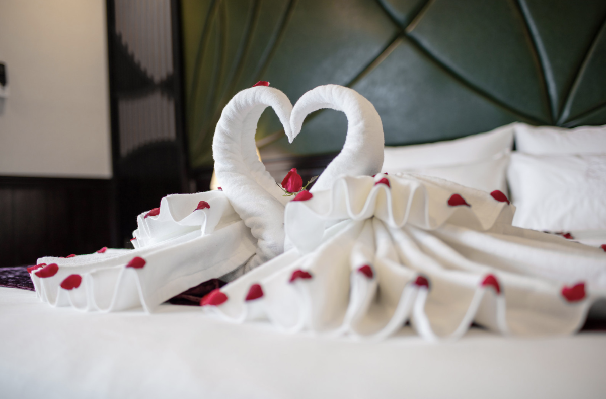 towels shaped like swan on top of a bed in one of the honeymoon hotel suites in Singapore